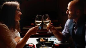 A man & woman toasting wine at a table in a restaurant having Valentines Dinner in Dublin.