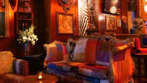 Exceptional event space featuring wooden-paneled walls adorned with vintage pictures, mismatched-colored luxurious seating, and soft lighting ambiance. One of the most popular cocktail bars in Dublin