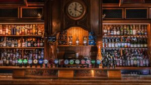 Mahogany bar with well-stocked wooden shelving displaying an array of spirits. In the foreground, a diverse selection of draft lagers, beers, and crafts. This historic venue stands as one of the oldest in Temple Bar Dublin