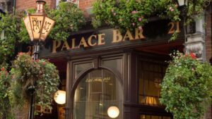 The exterior of the Palace Bar is adorned with a distinctive branded lantern stand at its entrance. The pub emanates a welcoming ambiance, enveloped in vibrant greenery and colourful plant arrangements. Adding to its charm is a sizable arched window positioned beneath the pub signage, contributing to the character and allure of this establishment in Temple bar, Dublin.