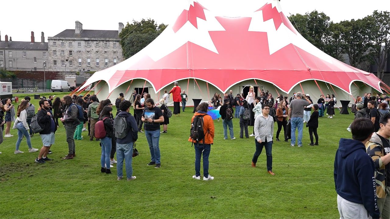 Large tent and open green space for corporate retreats in Ireland Spacious green area with a large tent in the background and groups of people walking around, ideal for corporate retreats in Ireland
