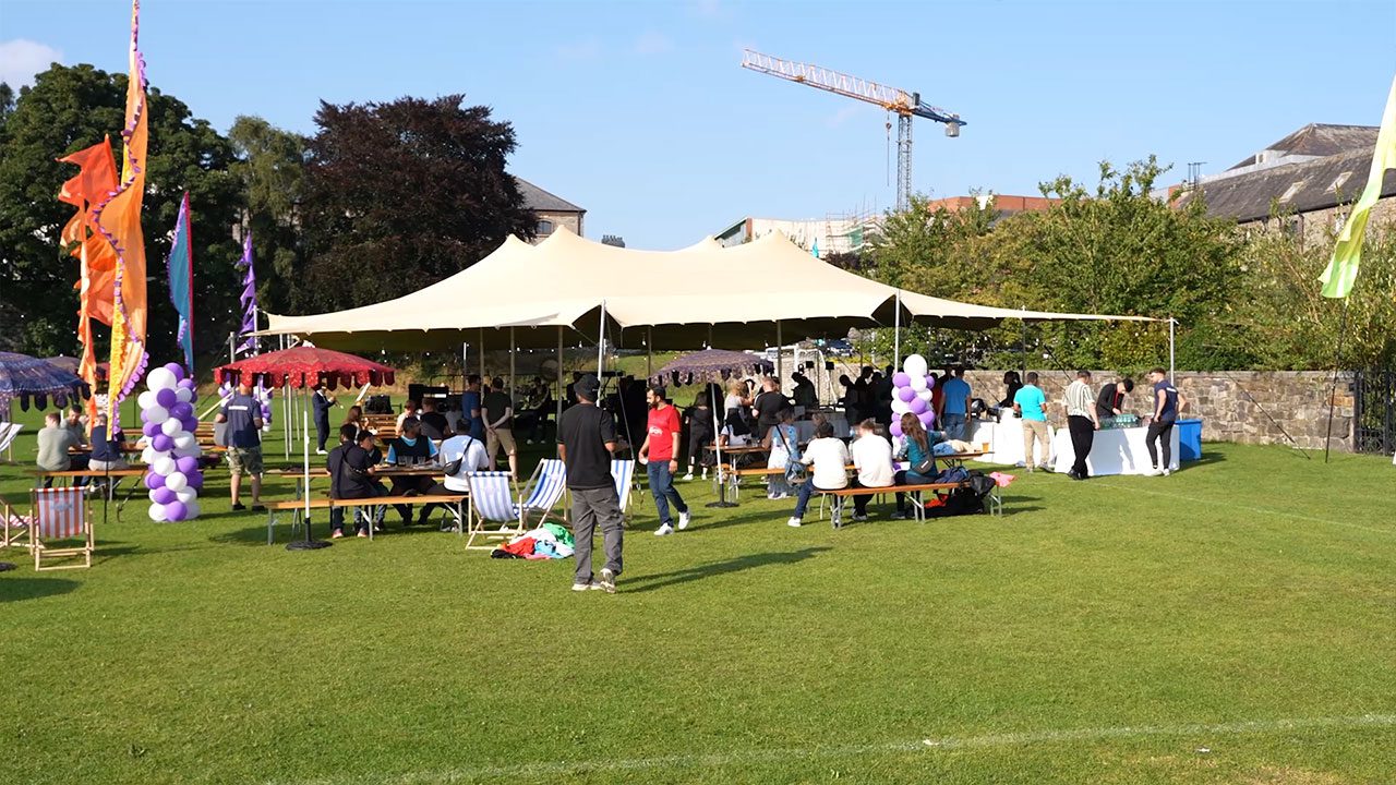 Outdoor tent setup for corporate retreats in Ireland Large marquee tent in a green area with guests dining inside and out, perfect for corporate retreats in Ireland