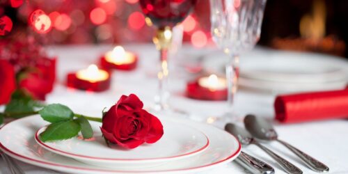 Table set in Sole Seafood Restaurant with white table cover and dressed with plates, cutlery and glasses. A red rose sits on one of the plates with small candles scattered over the table. One of the many venues with Valentines day offers in Dublin.